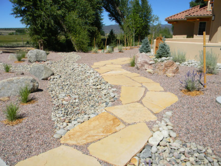 Flagstone walkway crossing over dry creek bed. Native plants supplied water by way of drip system.